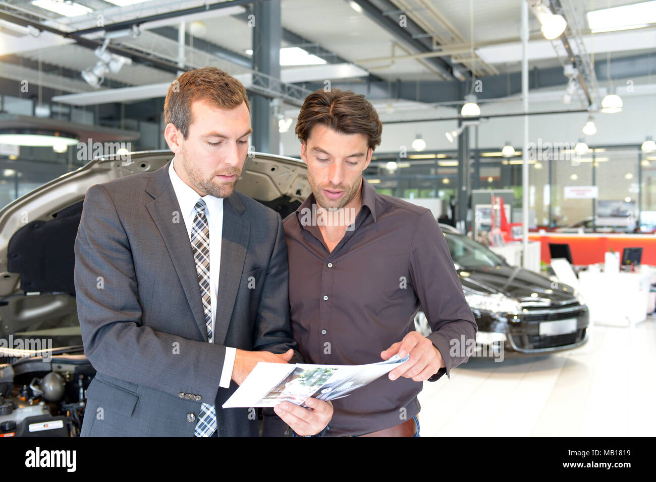 car salesmen and customers talk about the technology of a car in the