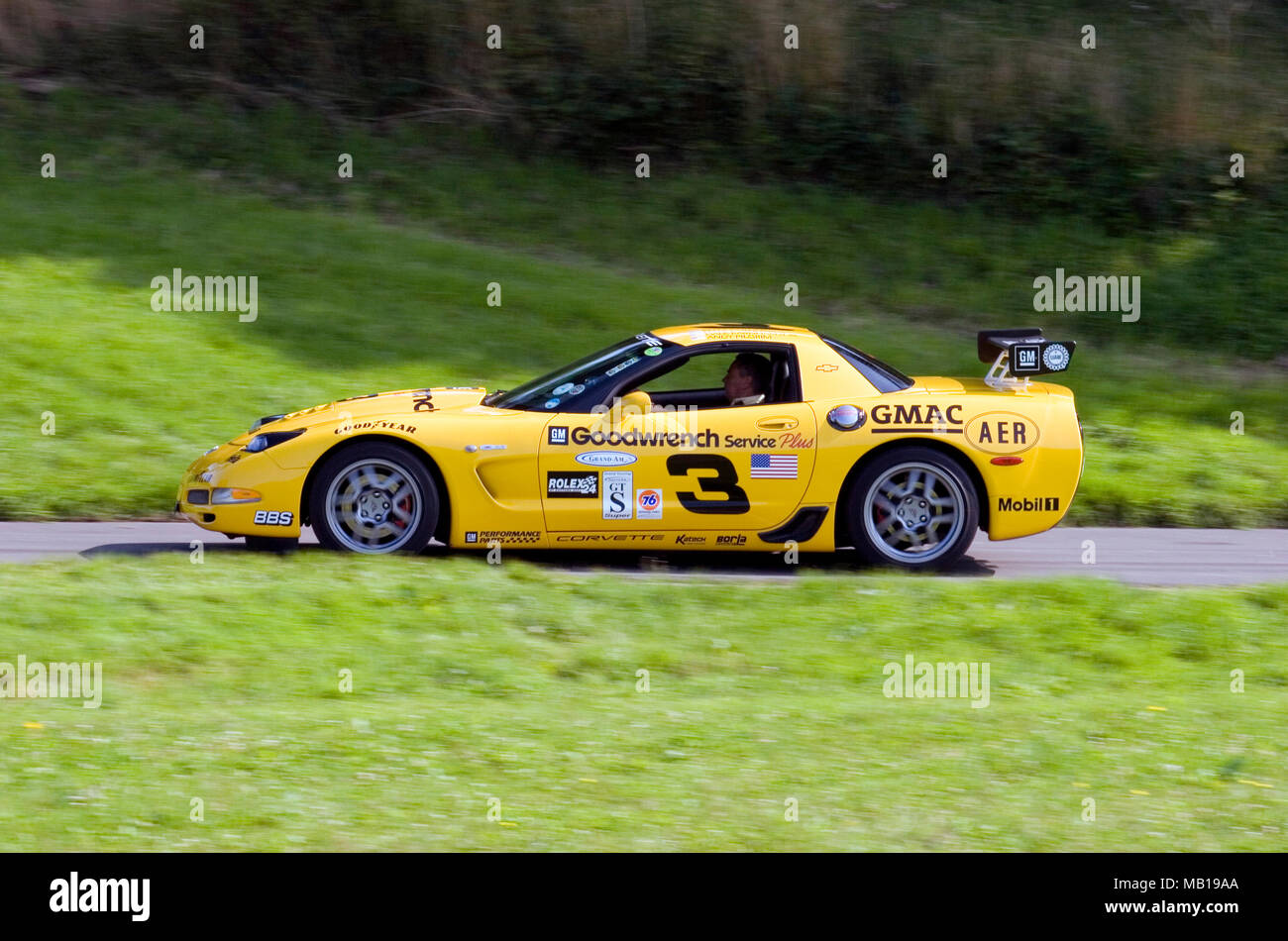Yellow Chevrolet Corvette racing car in profile (side view) and driving fast. Stock Photo