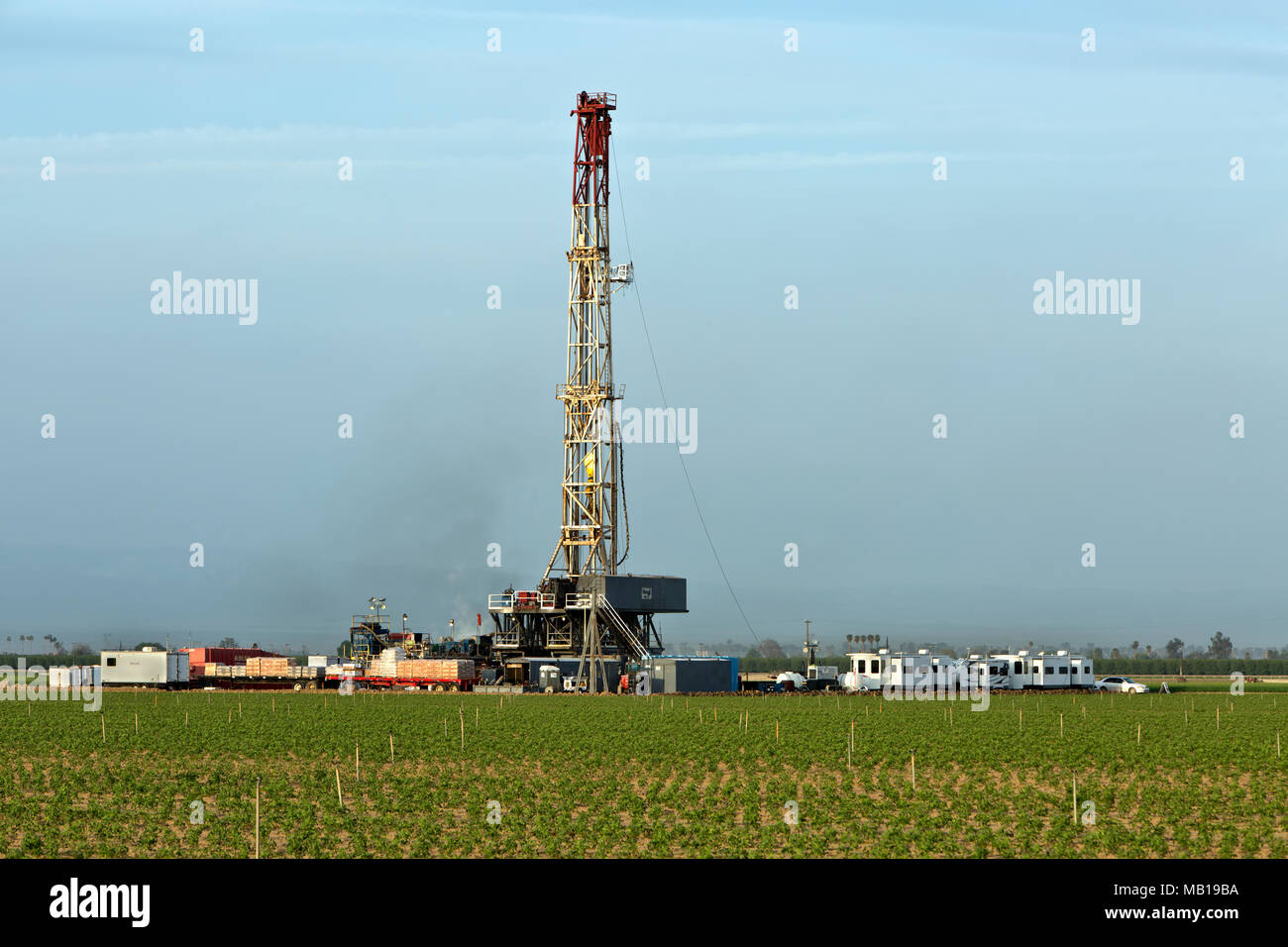 Drilling rig operating in productive tomato field in foreground. Stock Photo