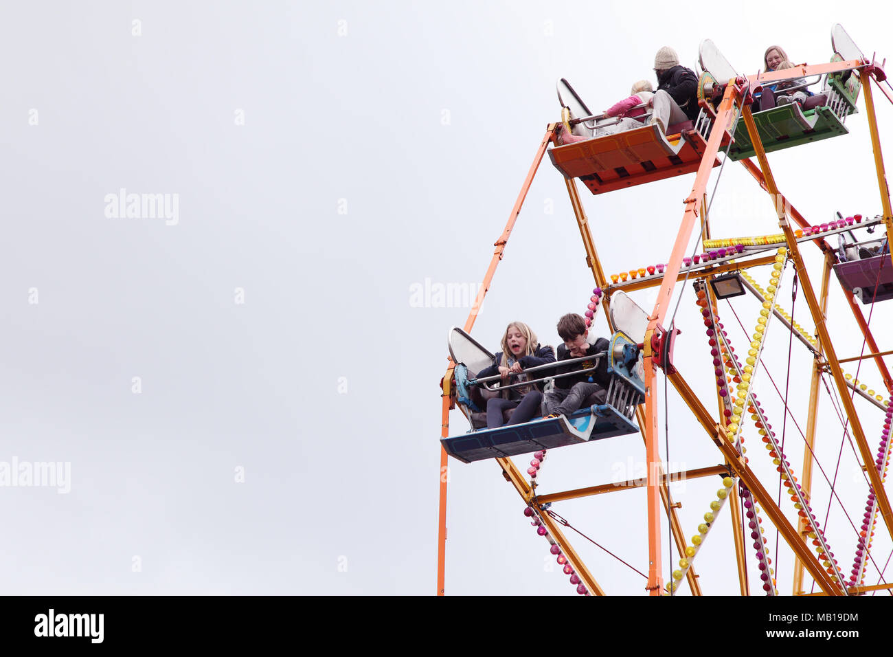 Children looking down and screaming on a fairground ferris wheel. Stock Photo
