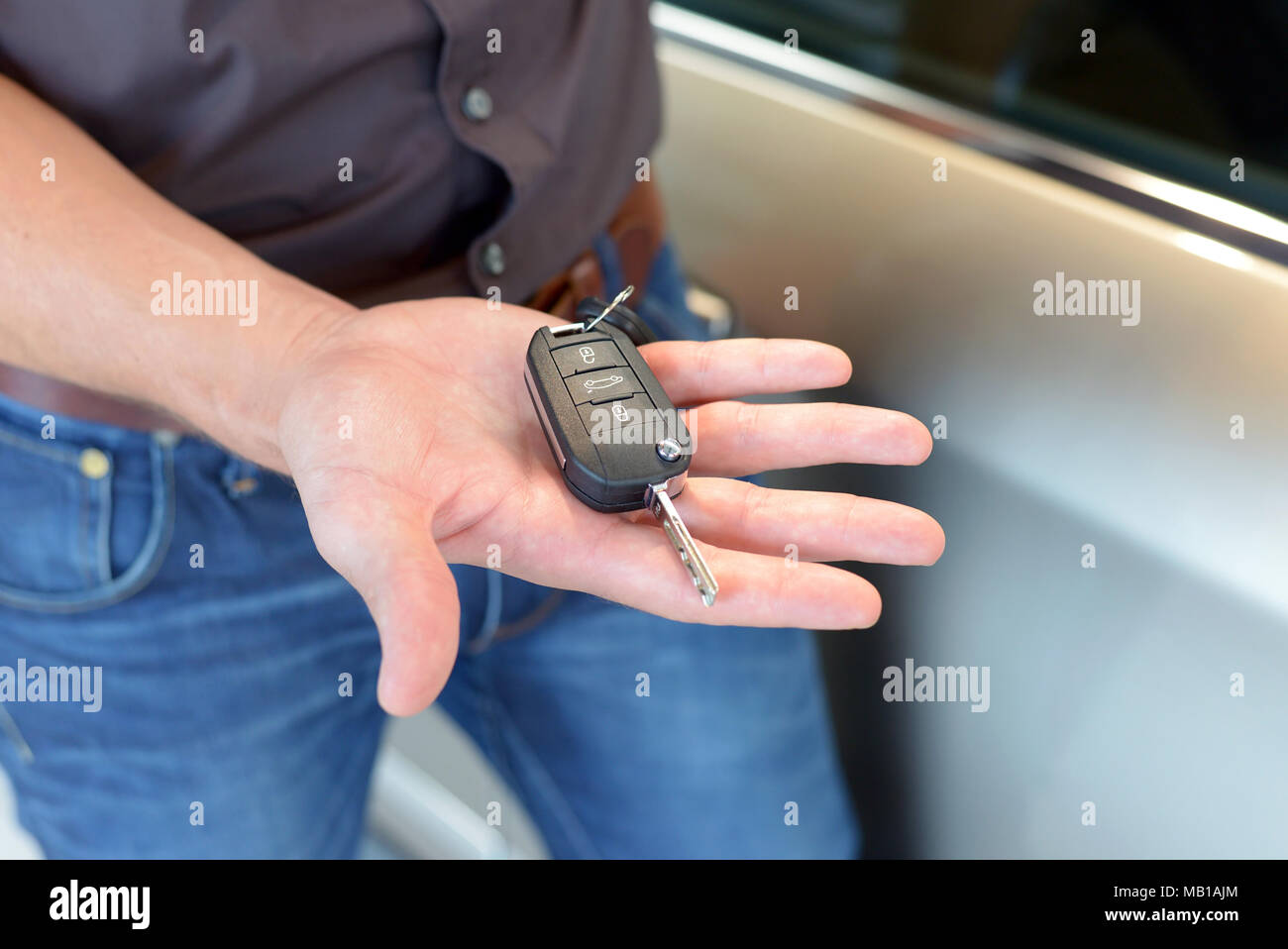 car salesman hands over the car key in the car dealership to customers Stock Photo