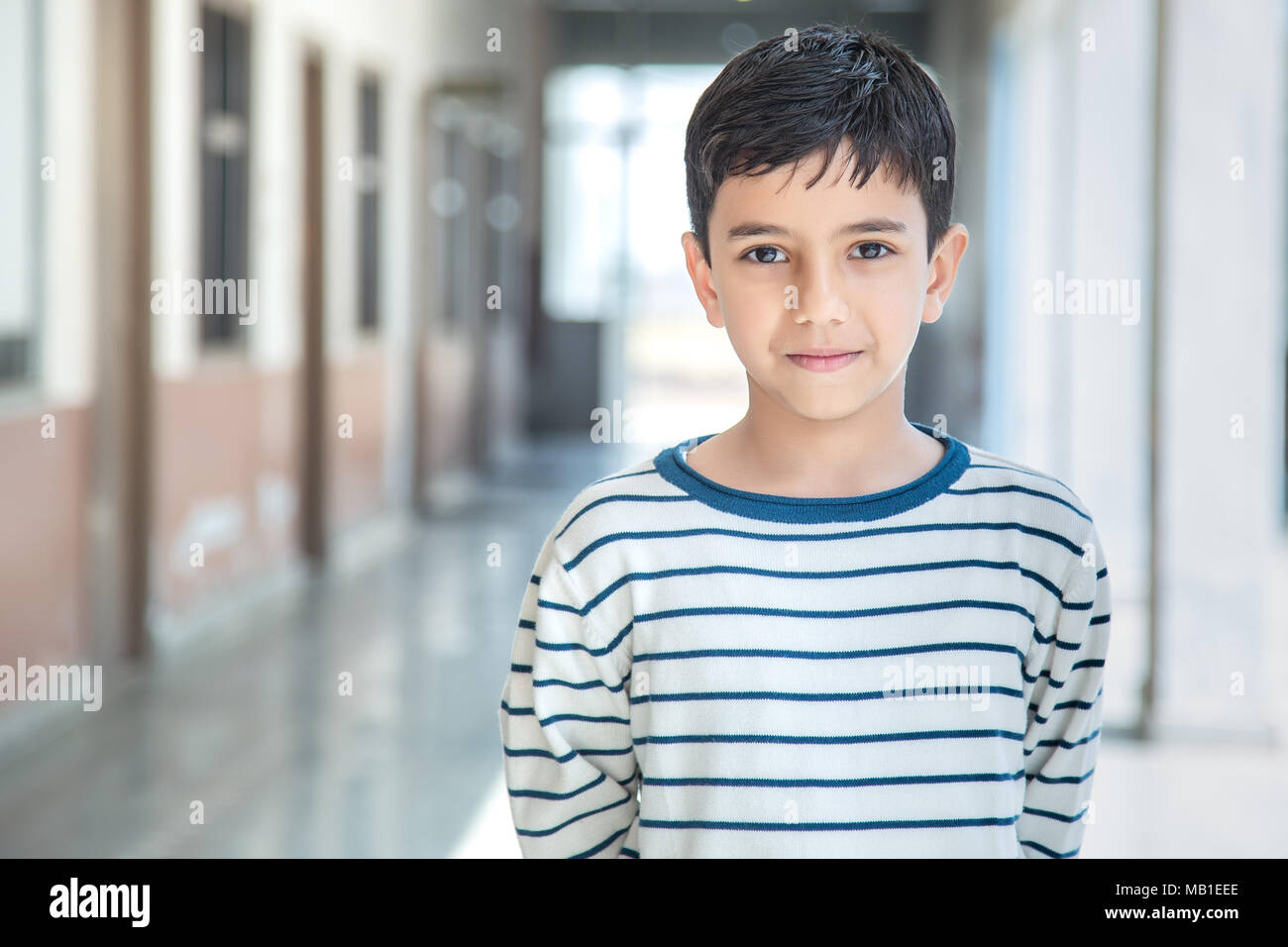 Portrait of smiling 6-7 years Indian kid, standing straight at school campus in school uniform and looking at camera Stock Photo