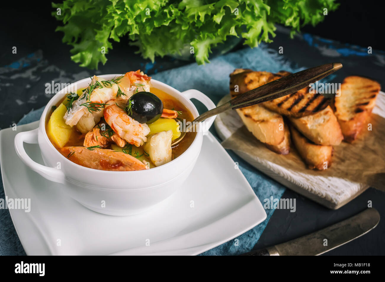 French fish soup Bouillabaisse with seafood, salmon fillet, shrimp, rich flavor, delicious dinner in a white beautiful plate. Close up. Stock Photo