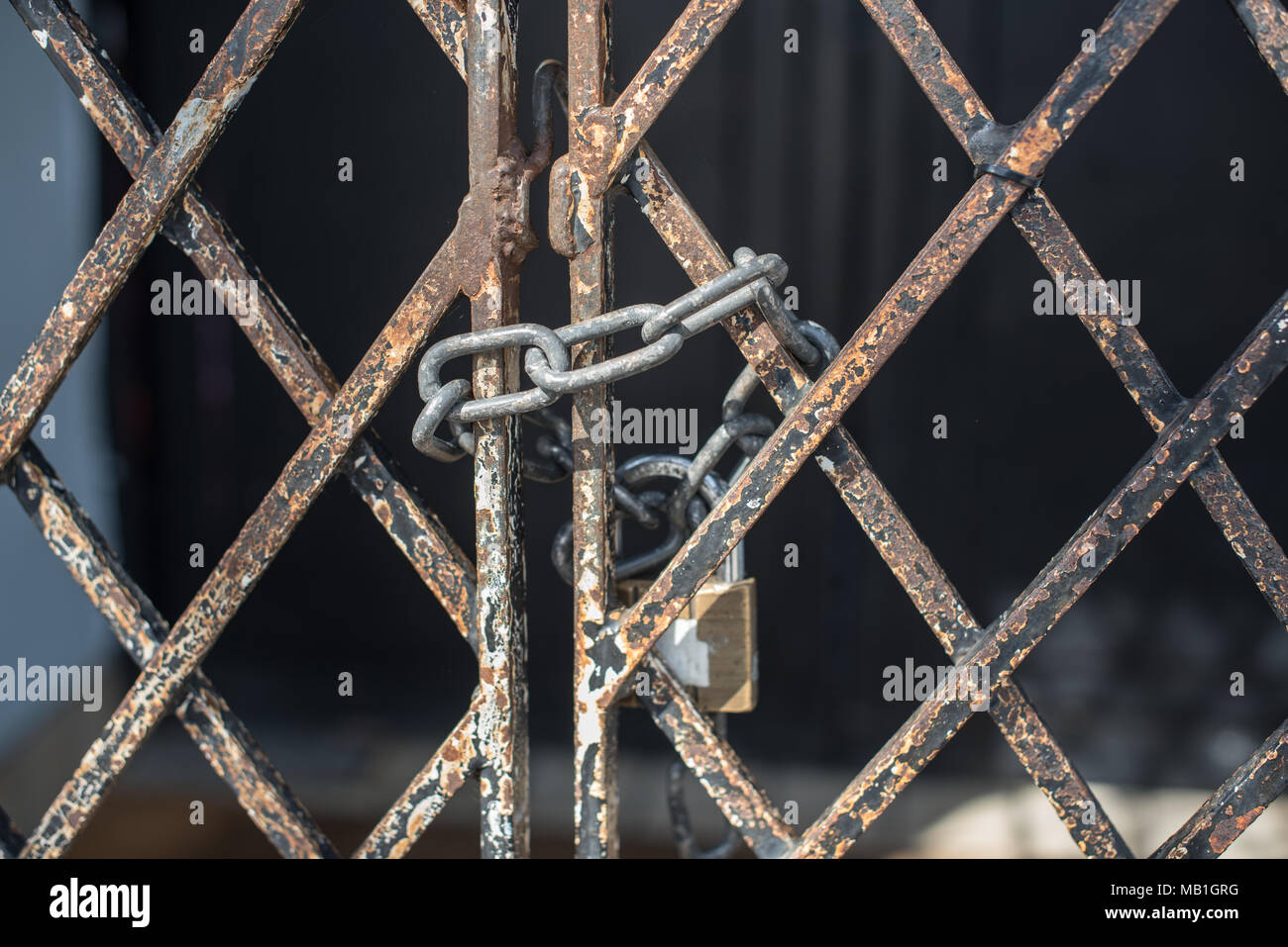 A padlock keeps rusty gates closed shut on an old abandoned shop on the high street in Newport in Shropshire, making sure people do not trespass Stock Photo