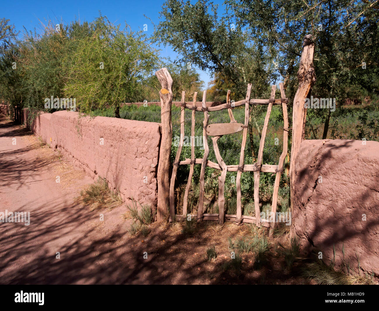 Adobe walls and a wooden gate enclose a field of Alfalfa, San Pedro de Atacama, Chile Stock Photo