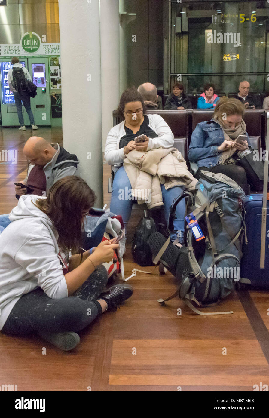 people in Eurostar waiting room of St Pancras station, London, England, all using mobile phones Stock Photo