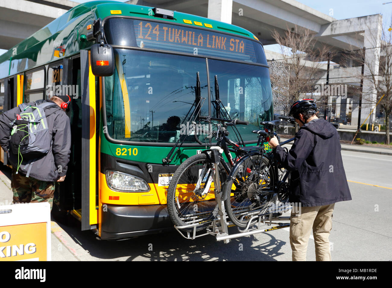 A bicyclist places a bike on a King Country Metro Transit bus bike rack in Seattle, Washington Stock Photo