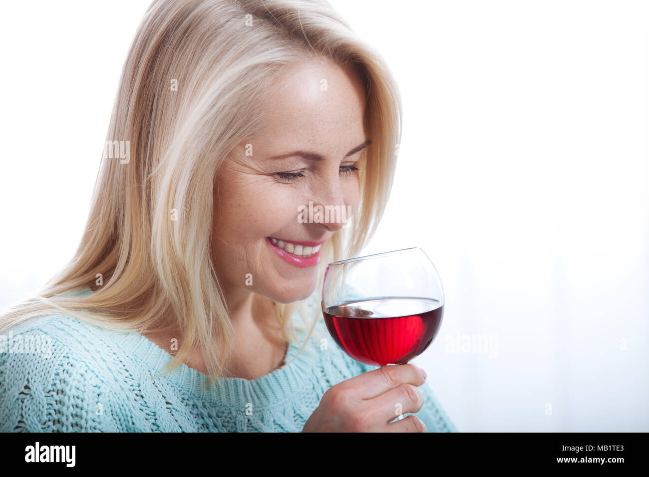 Happy blonde drinking red wine with eyes closed. Stock Photo