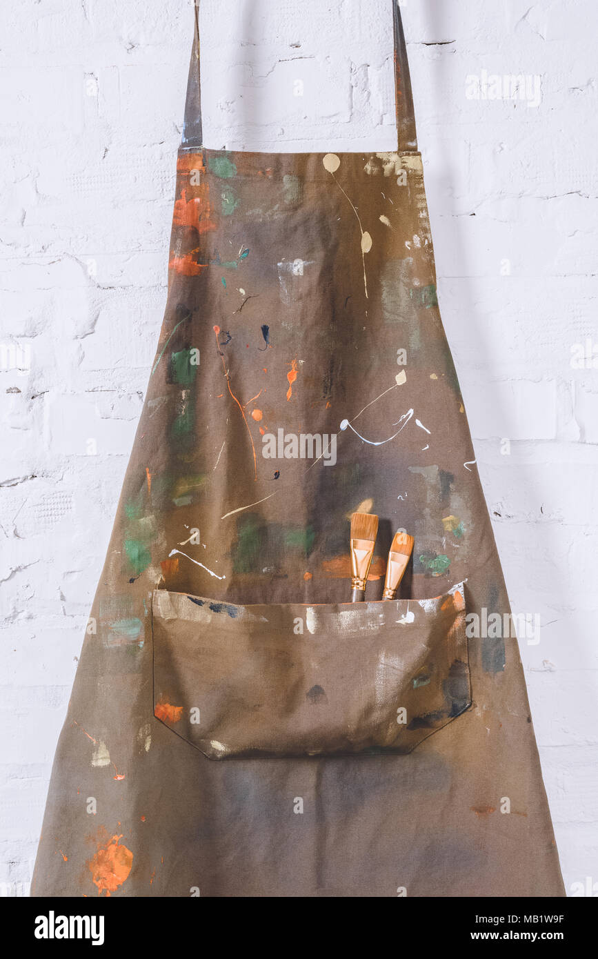 artist apron with paint brushes hanging on brick wall Stock Photo - Alamy