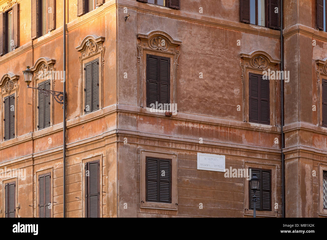 Windows and wooden shutters on the terracotta coloured walls of a building on the corner of 'Scalinata della Trinita dei Monti' (The Spanish steps) Pi Stock Photo