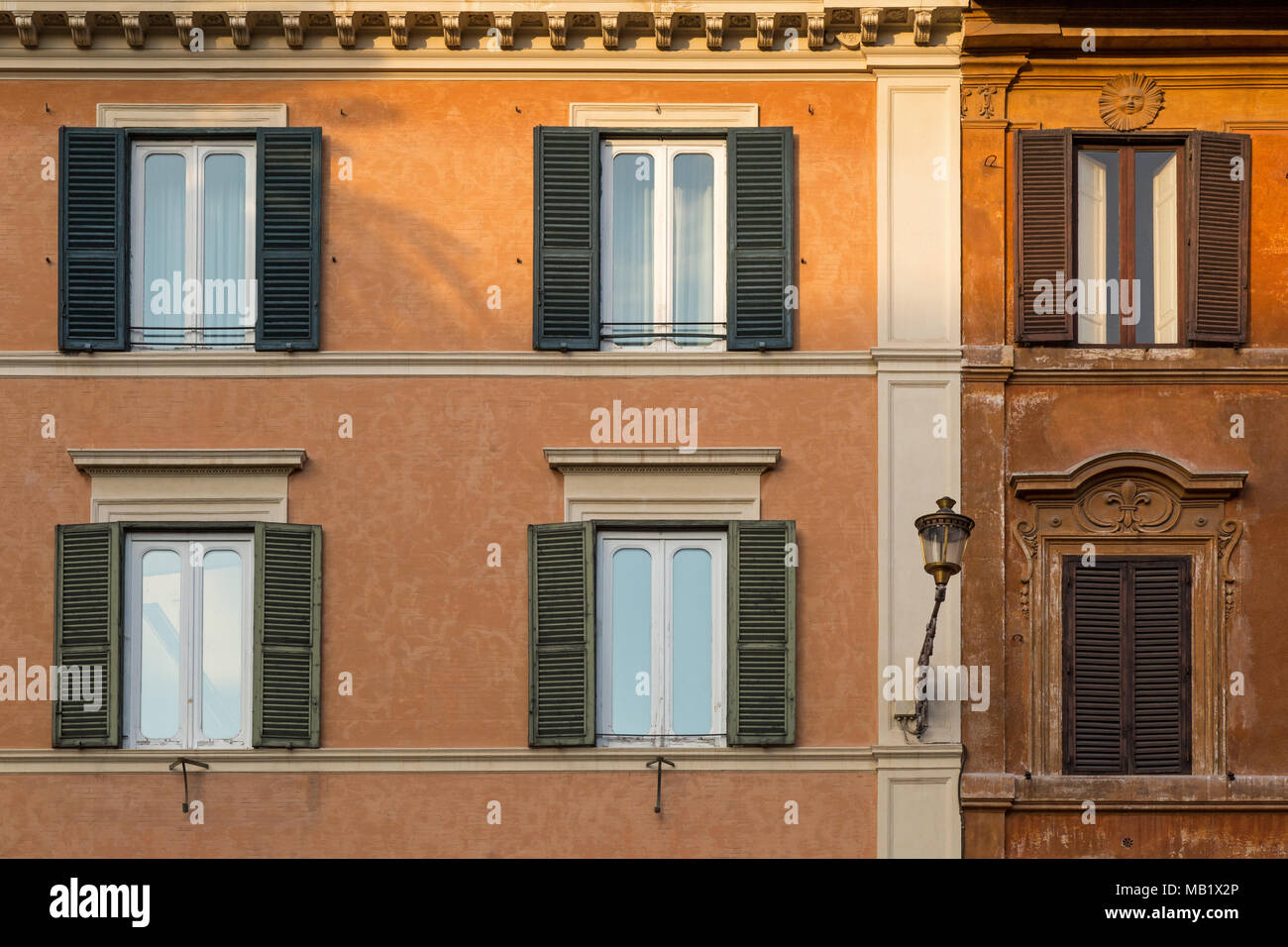 An ornate sun plaque above one of the windows on a building in Rome, Italy, as it catches the last of the days sunlight. Stock Photo