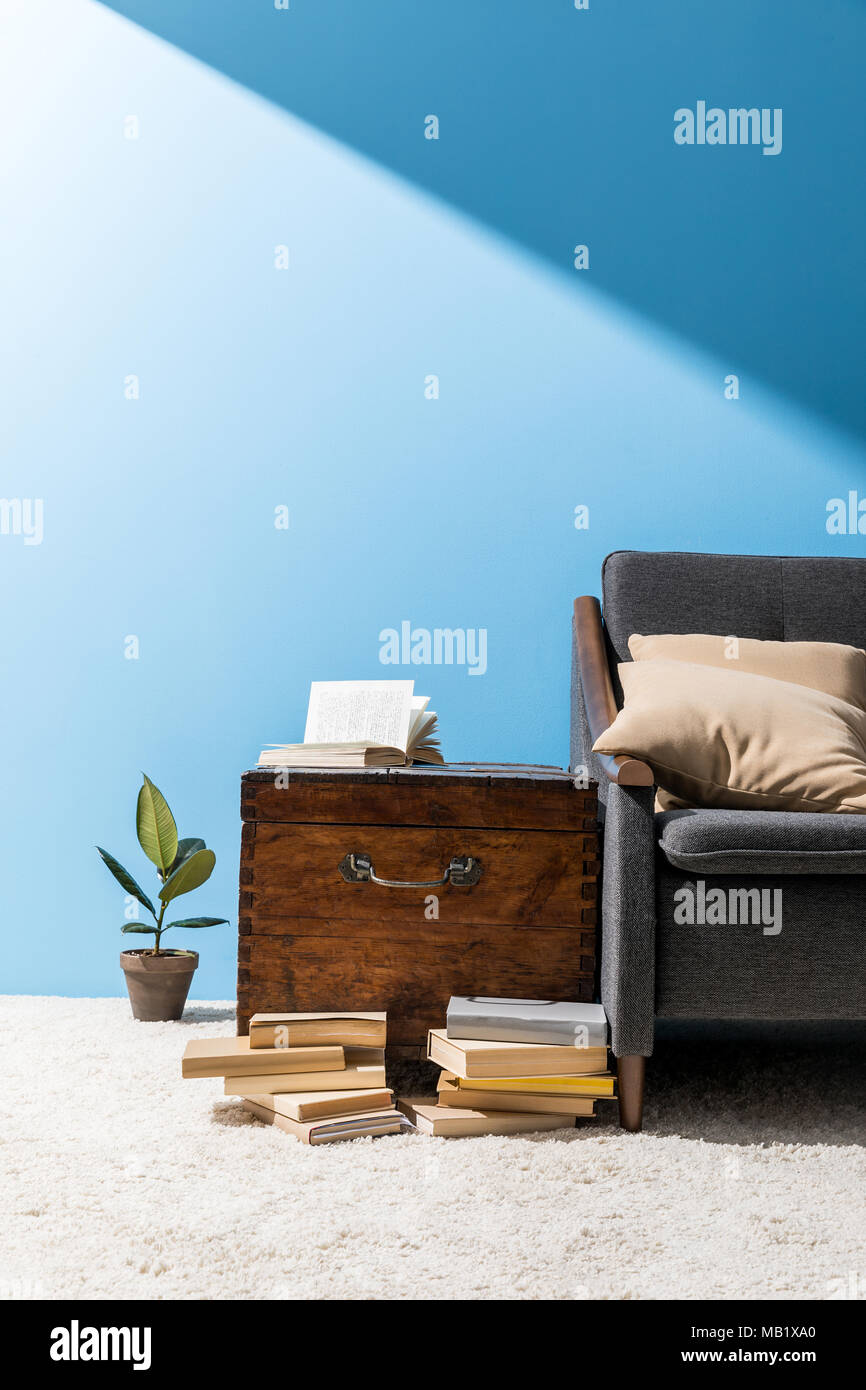 old wooden chest with books near couch in front of blue wall Stock Photo