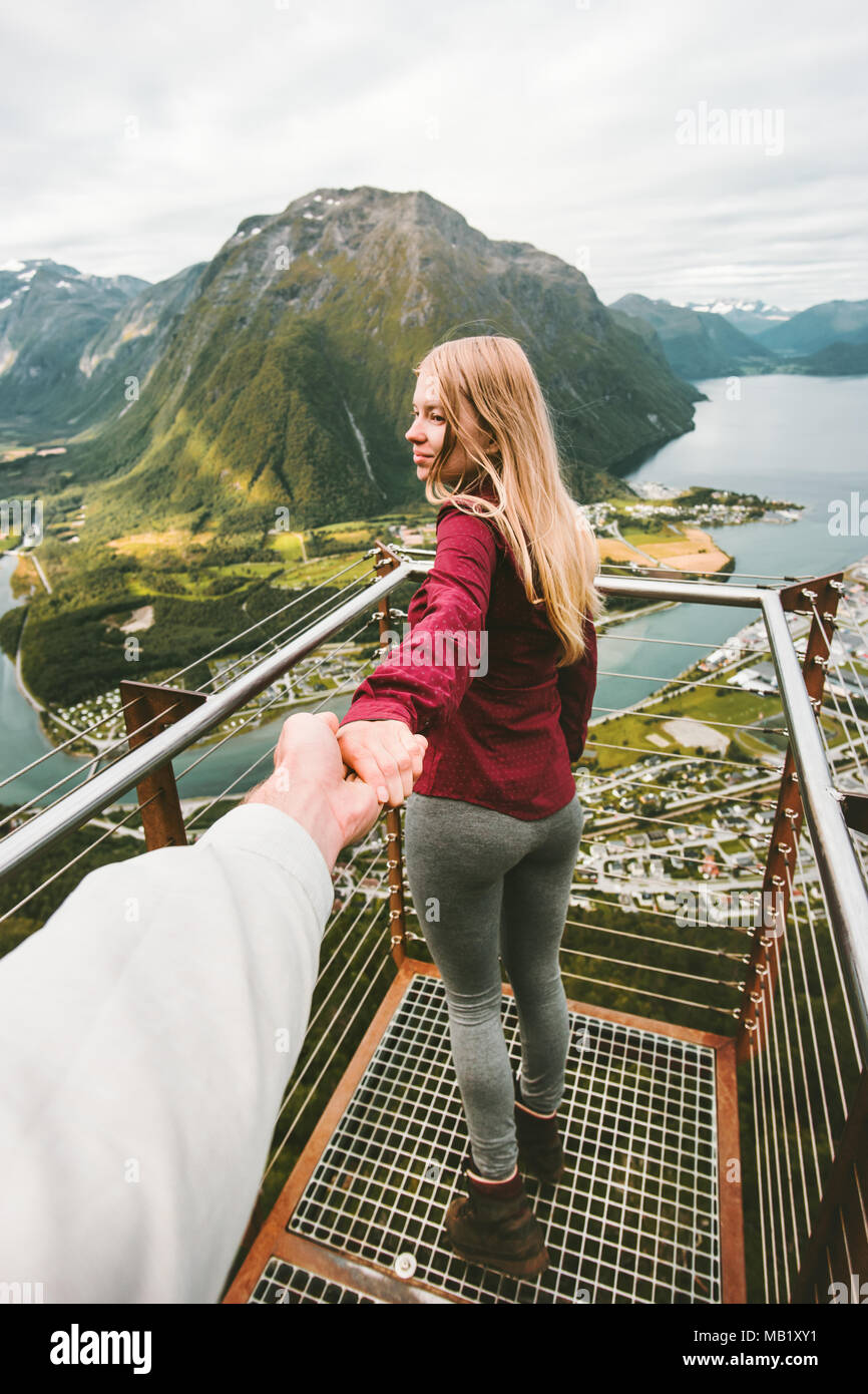 Couple Man and Woman follow me holding hands sightseeing mountains Travel happy emotions Lifestyle adventure vacations in Norway Rampestreken aerial v Stock Photo