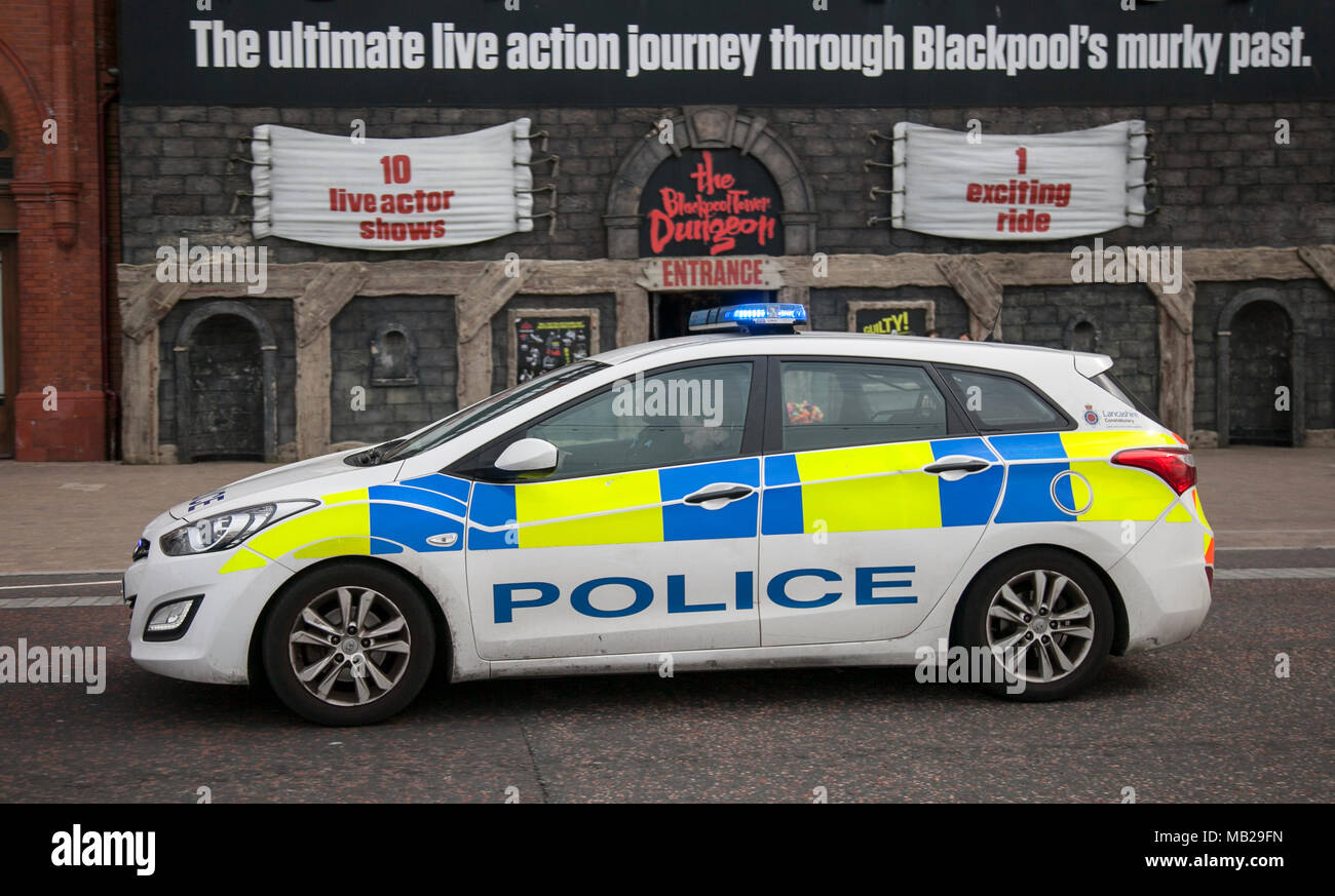Police car passing seaside attractions on Blackpool seafront  UK Weather: Cold & blustery on the Fylde Coast. The resort remains quiet as holidaymakers stay away from the seaside attractions. Credt:MediaWorldImages/AlamyLiveNews Stock Photo