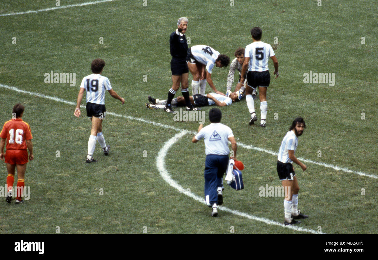 FIFA World Cup - Mexico 1986 25.6.1986, Estadio Azteca, Mexico, D.F. Semi-final Argentina v Belgium. Referee Antonio Mquez Ramez (Mexico) calls for the stretcher as Htor Enrique lays injured on the pitch, Ricardo Giusti, Nery Pumpido & Jos Luis Brown (5) are the first to help. On left Oscar Ruggeri, on right Sergio Batista. Stock Photo