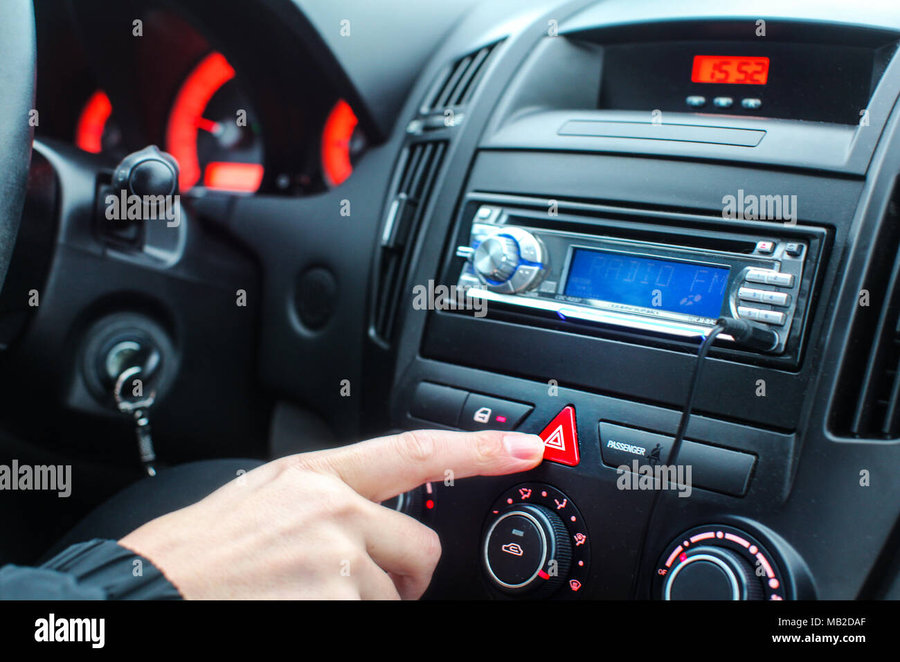 Detail on car dashboard, man finger pressing the emergency lights button while driving Stock