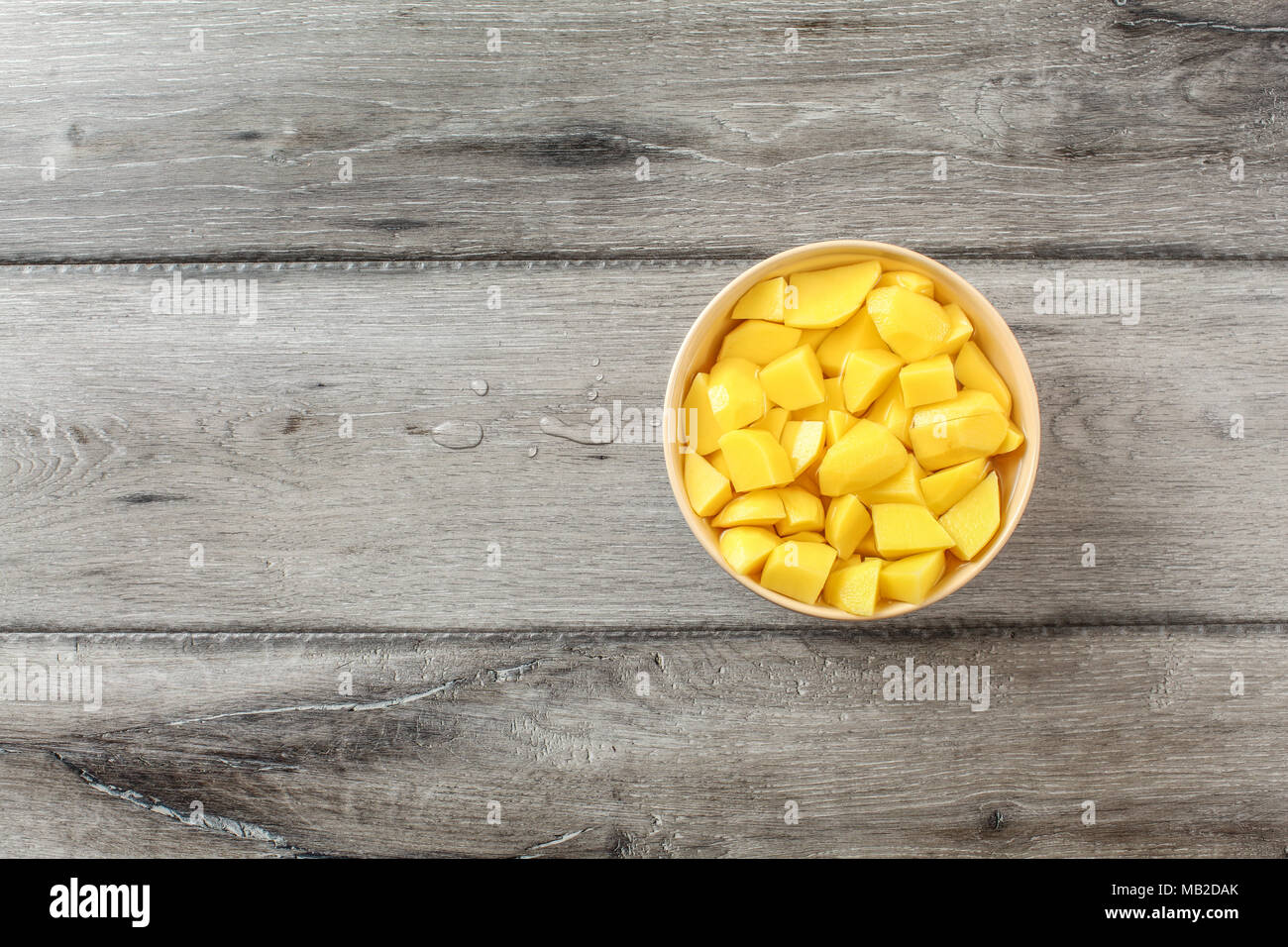 Table Top View On Raw Potatoes Cut In Small Pieces In Beige Bowl