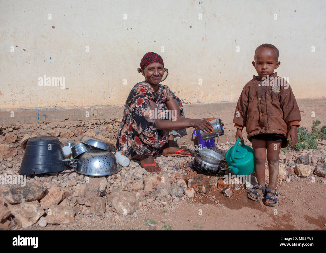Somali mother with her son washing kitchen tools outside of her home, Woqooyi Galbeed province, Baligubadle, Somaliland Stock Photo