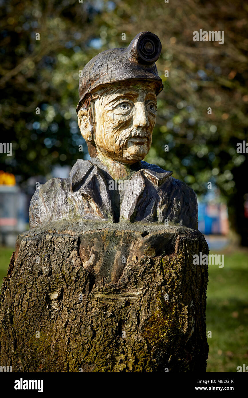 Mining history Mosley Common Village near Leigh, chainsaw sculptor Andy Burgess Miner Bust Sculpture from diseased tree the village green Greater Manc Stock Photo