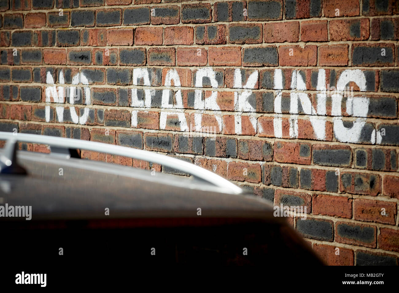 No Parking sign, notice hand painted onto a house wall in white paint Stock Photo