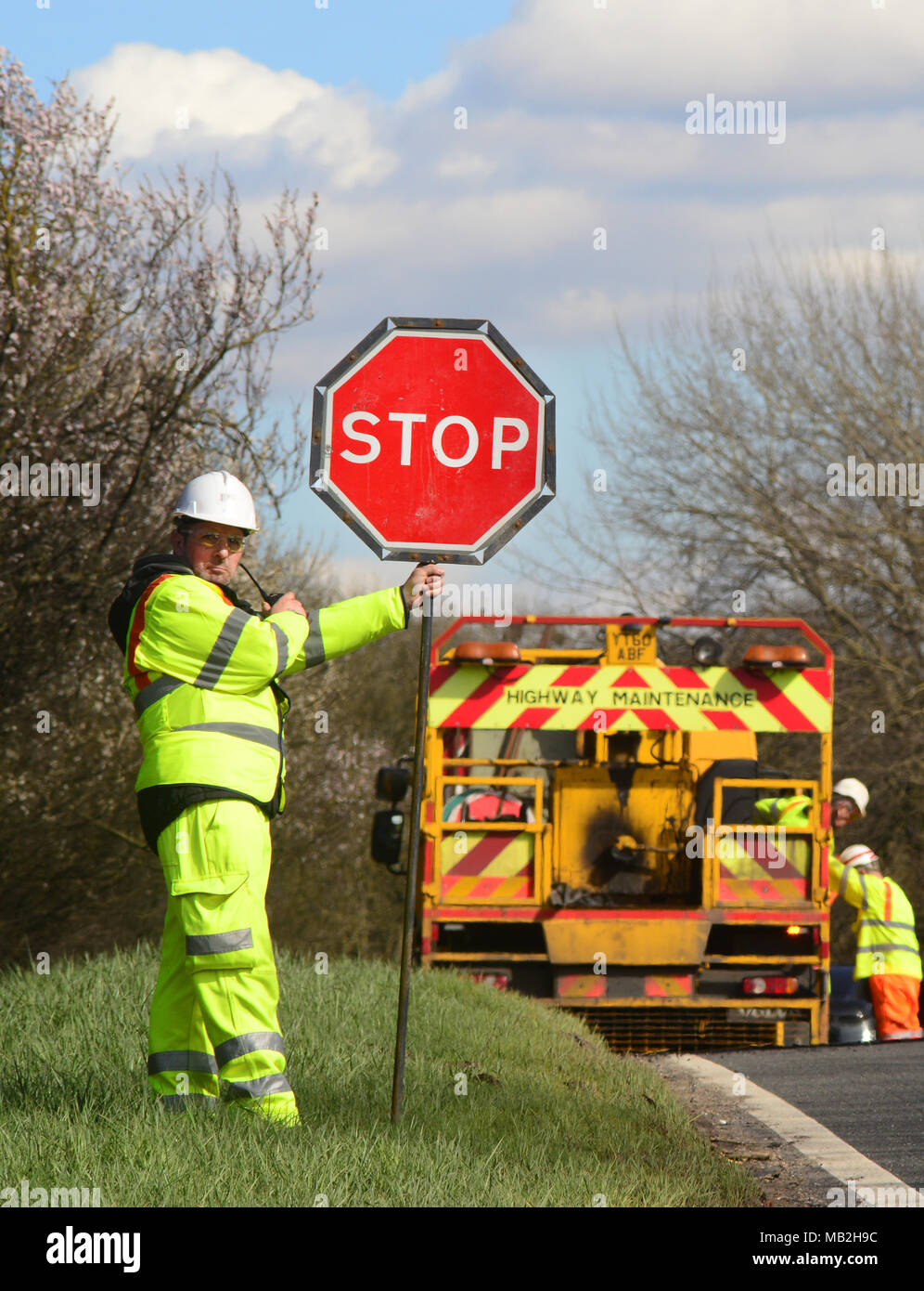 construction worker using lollipop stop - go sign to control traffic at roadworks united kingdom Stock Photo