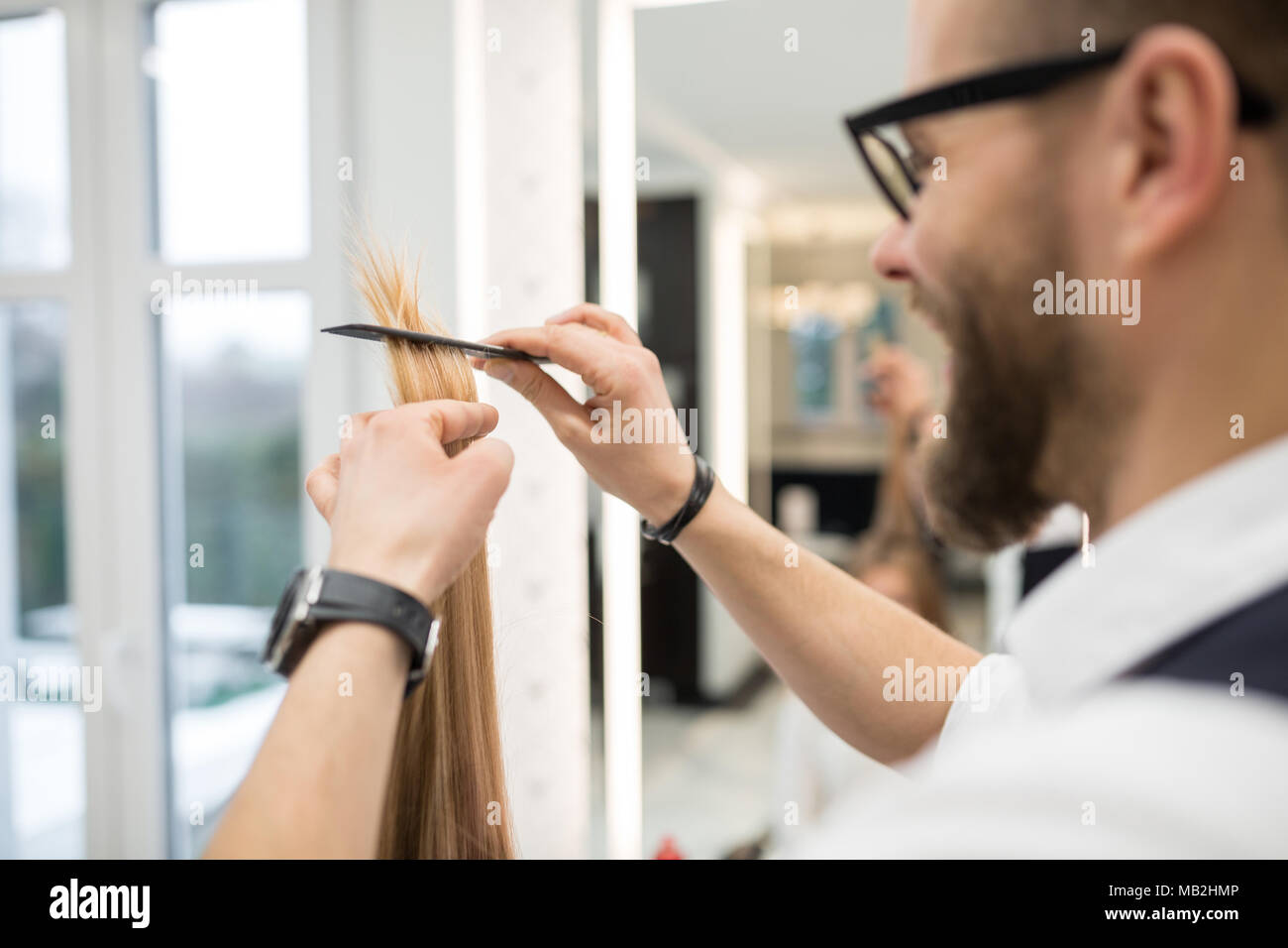 Portrait of happy hairdresser combing customer hair strand Stock Photo