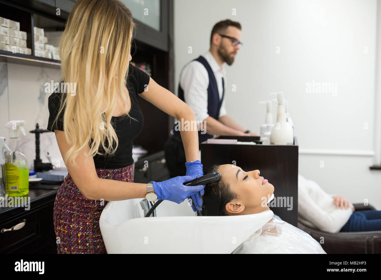 Portrait of hairdresser washing young woman hair Stock Photo
