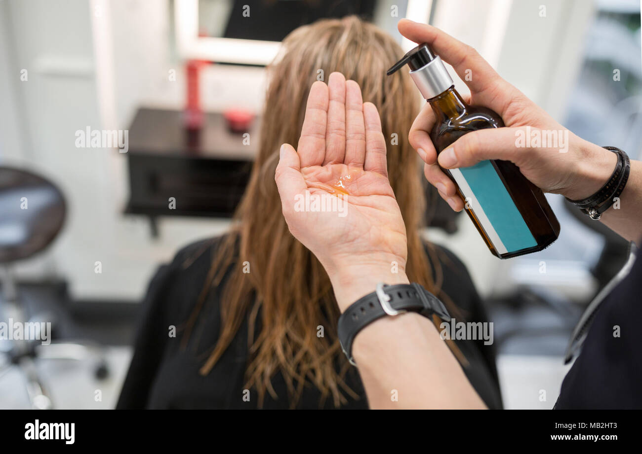 Cropped portrait of hairdresser squeezing hair conditioner on hand Stock Photo