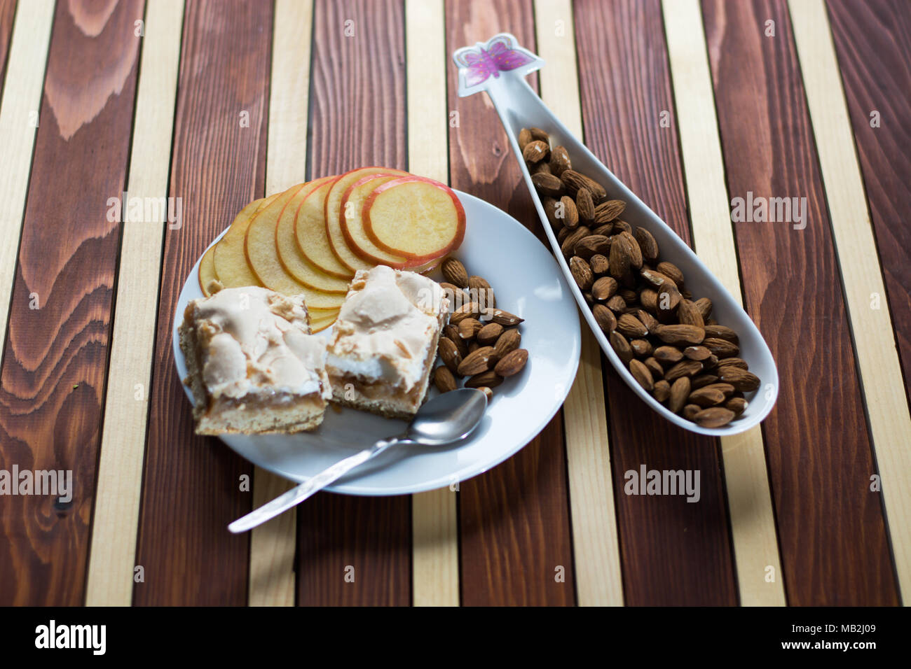 Square shape sliced omemade apple pie with kumquats and almonds on wooden background Stock Photo