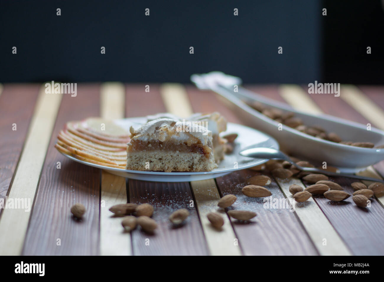 Square shape sliced omemade apple pie with kumquats and almonds on wooden background Stock Photo