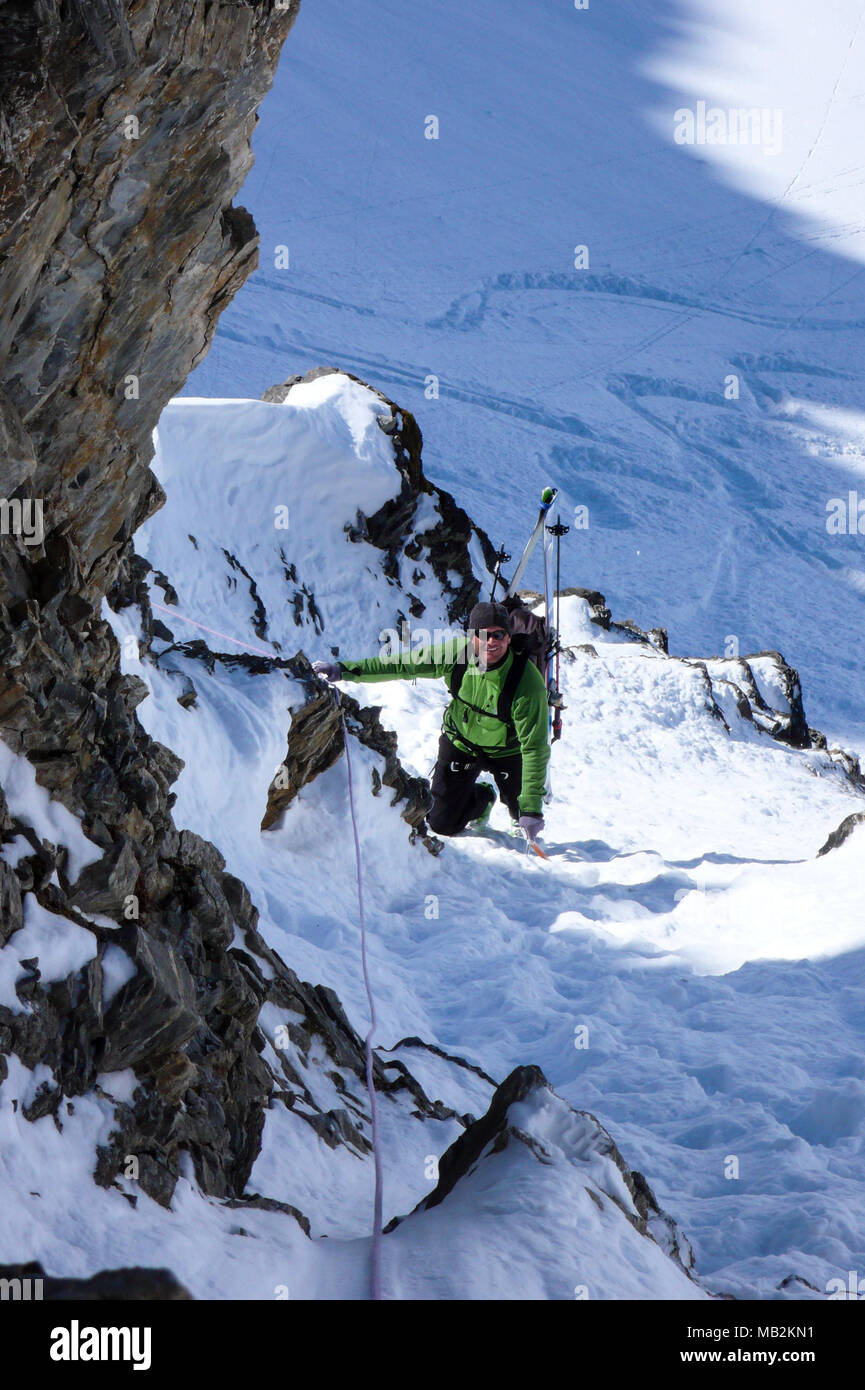 Backcountry Rappel mountain guide on a backcountry ski tour rappelling down into and ...