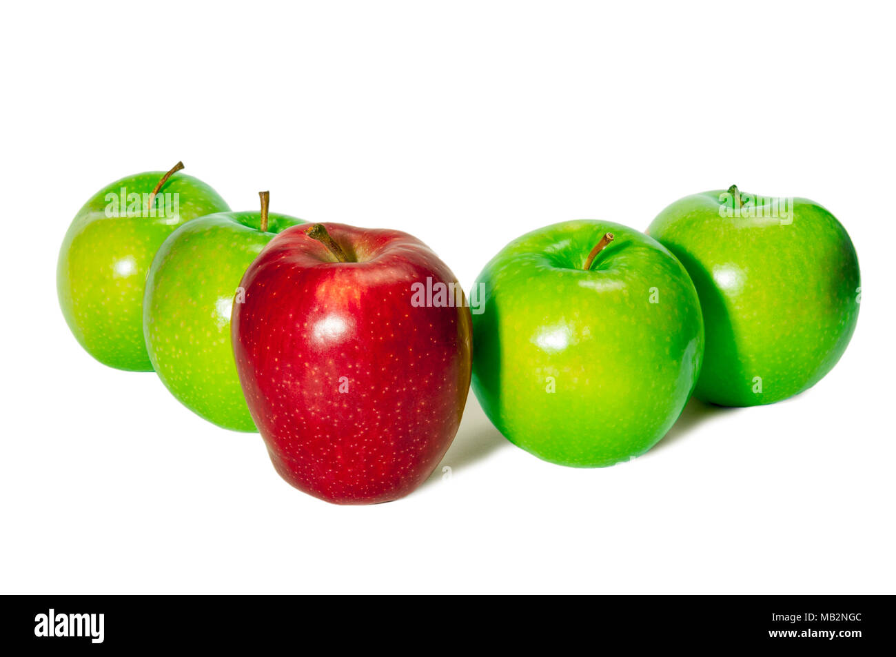 Horizontal shot of a red delicious apple standing in front of four green granny smith apples on a white background. Stock Photo