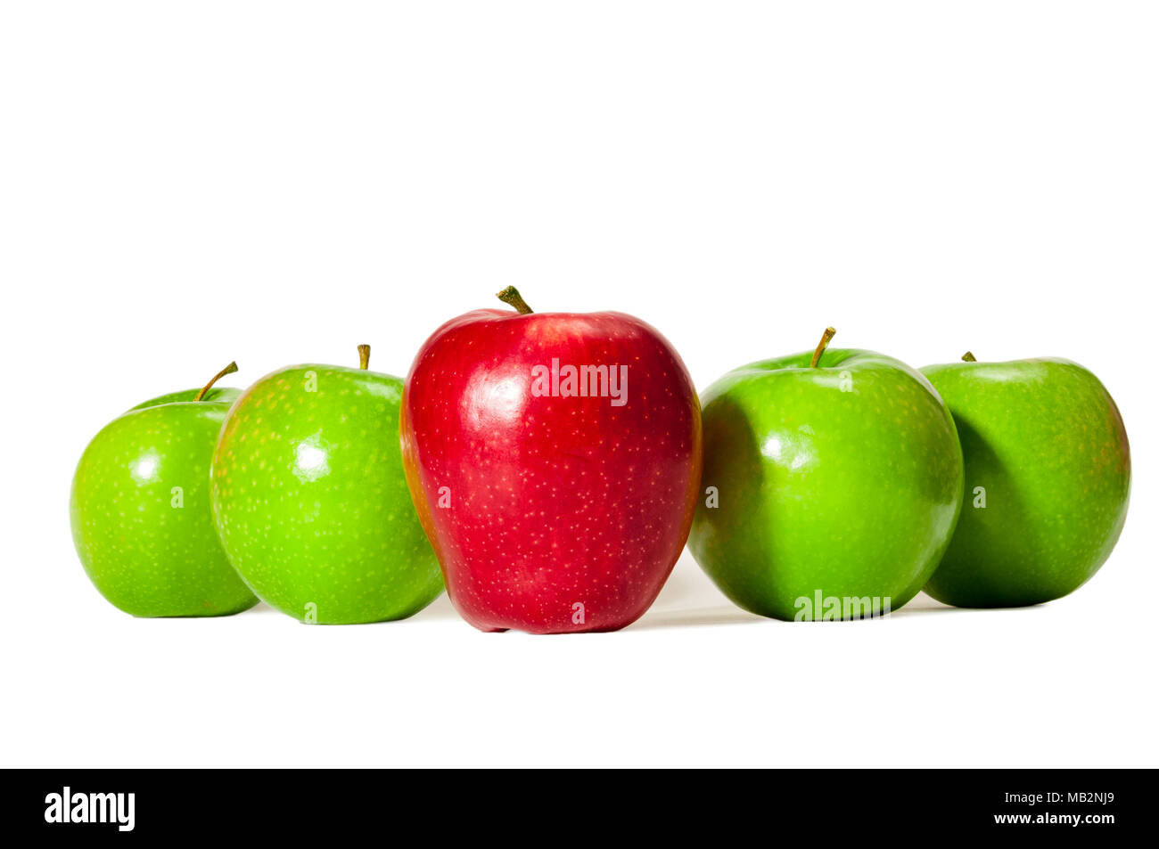 Horizontal straight on shot of one red delicious apple standing in front of four green granny smith apples on a white background. Stock Photo