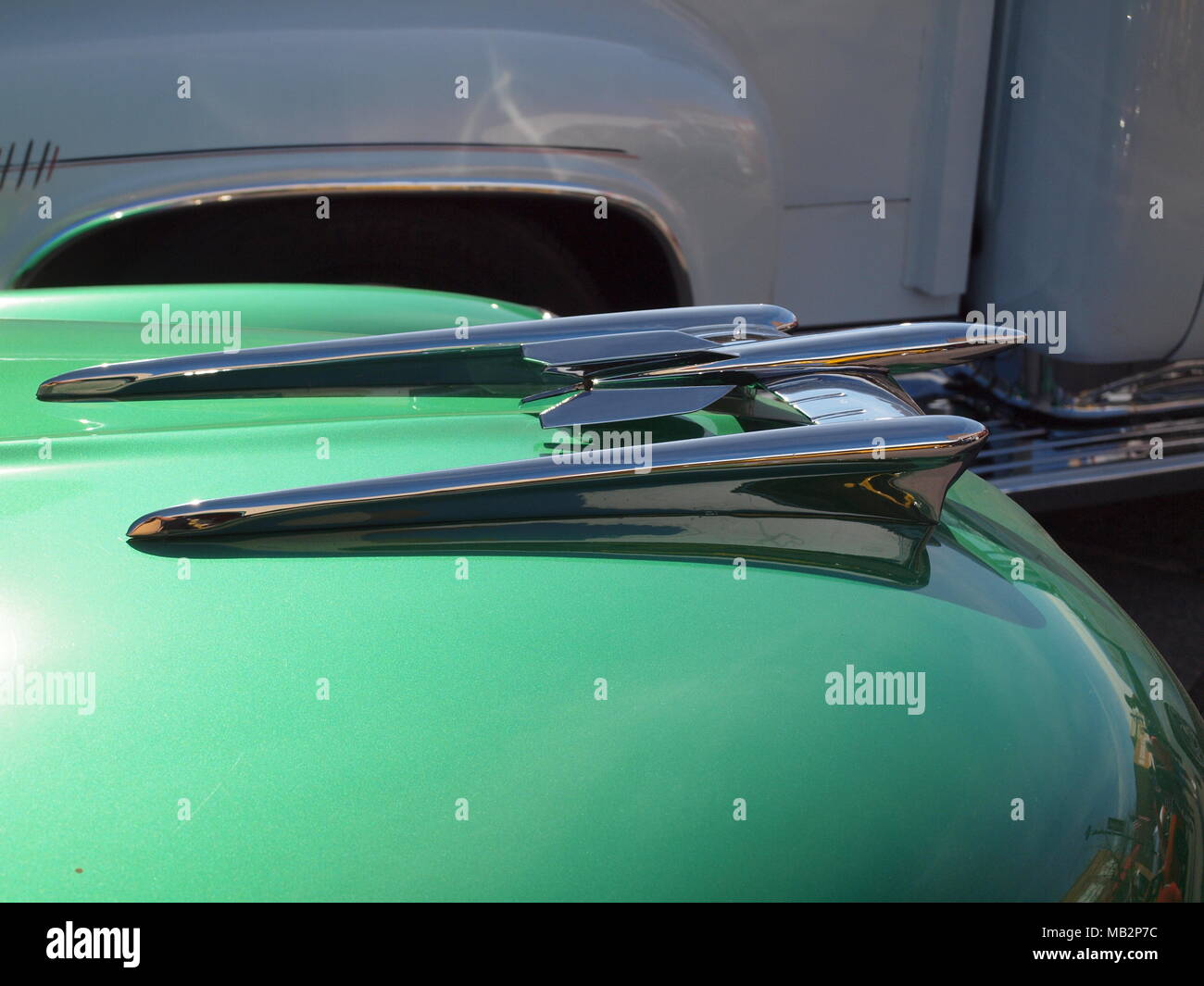 Gleaming chrome hood ornament on green hood. Stock Photo