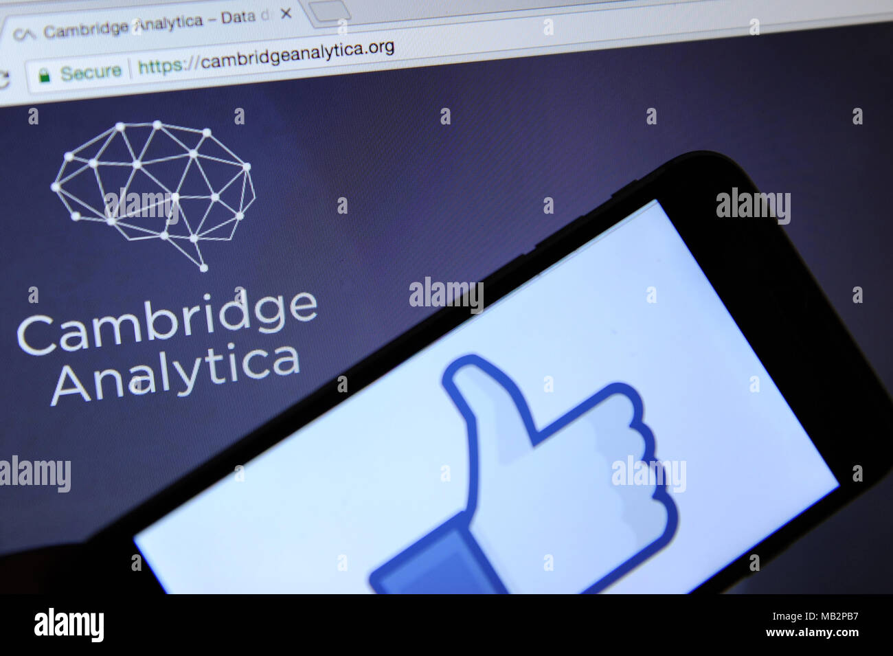Cambride Analytica website on a computer screen and the Facebook 'like' symbol on a phone Stock Photo