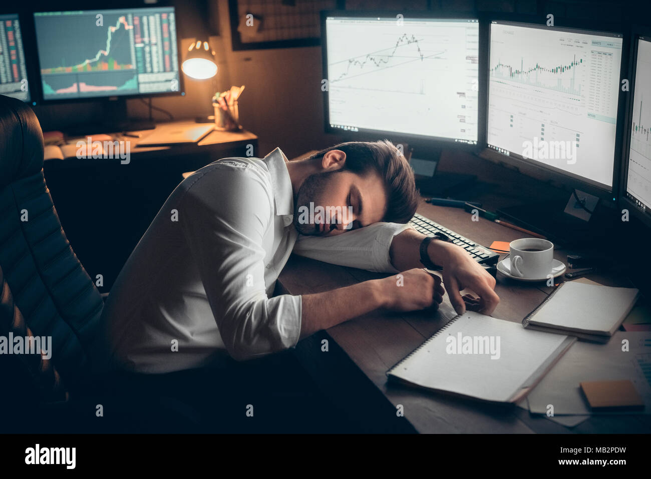 Young bearded man trader at office sitting at table sleeping tired hard-working Stock Photo