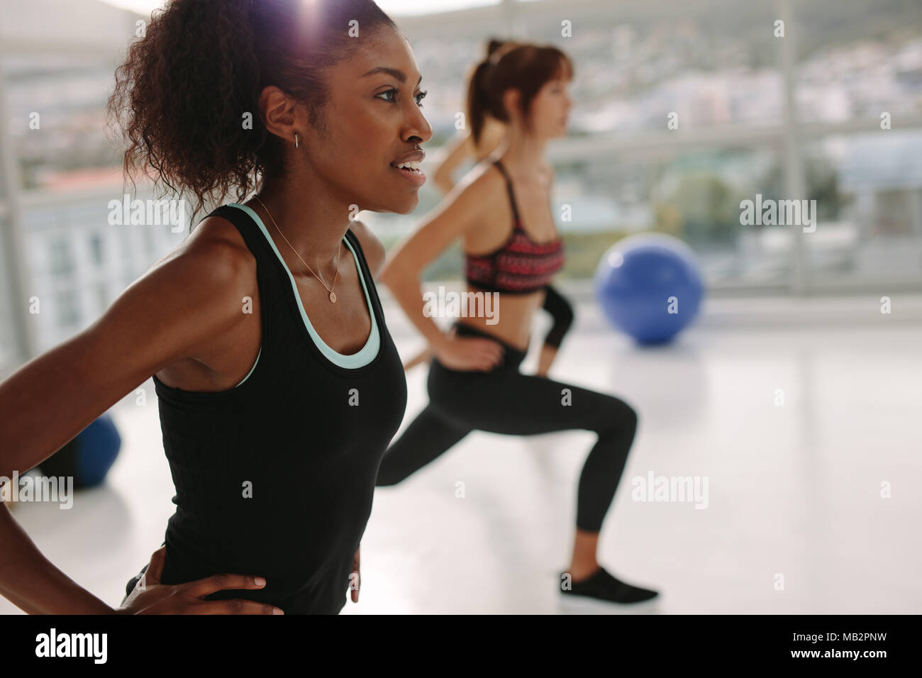 African young woman exercising in gym class. Stretching workout session in health center. Stock Photo