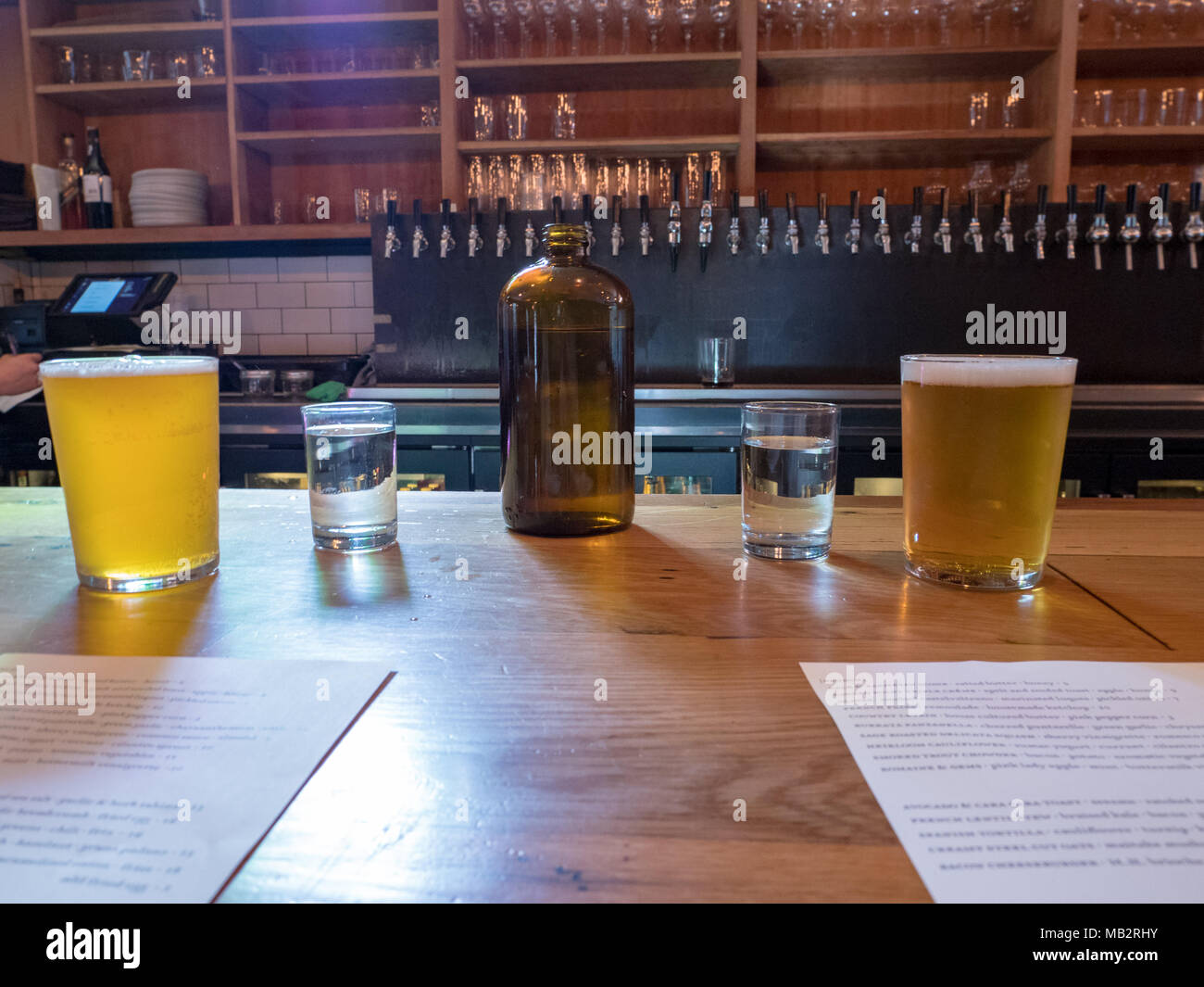 Water jug, cups, beer, brunch menus on bar counter in brewery Stock