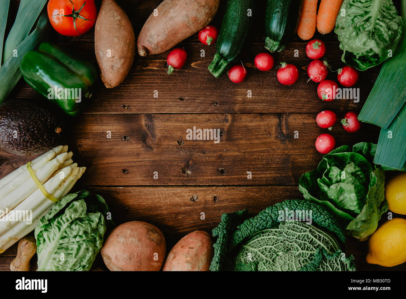 Top view of wooden table with healthy green vegetables arranged in pile ...