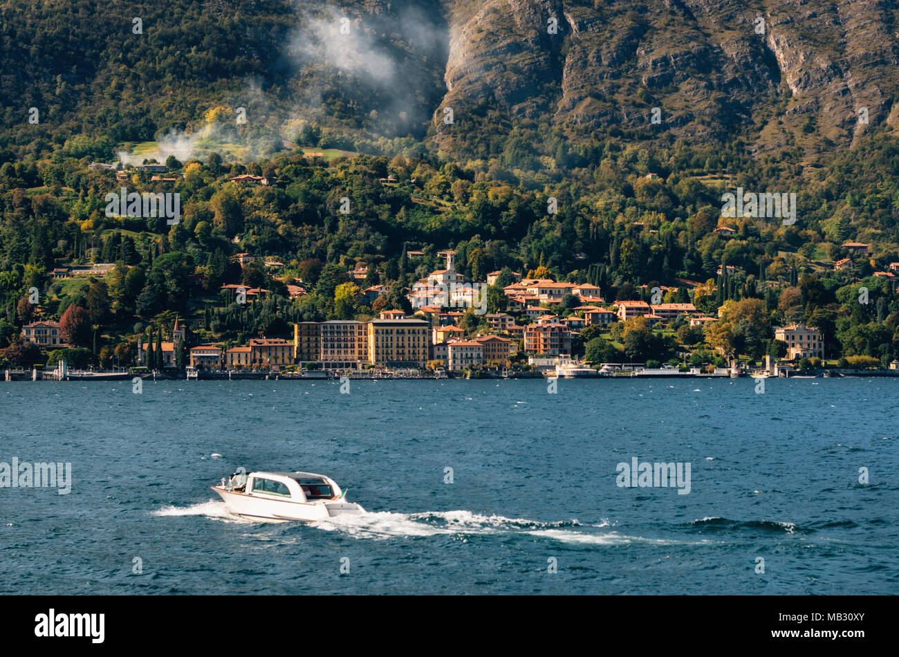 Boat moves against Cadenabbia town with buildings and hotels, coast of beautiful Como lake, Italy. Stock Photo