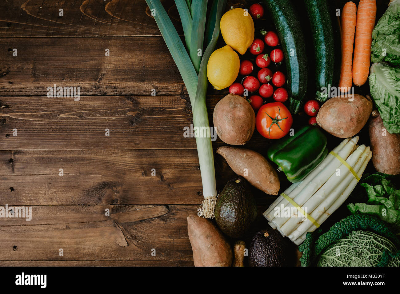 Top view of wooden table with healthy green vegetables arranged in pile ...