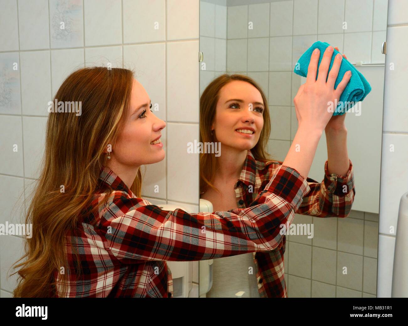House work, young woman cleaning mirrir in a bathroom, Sweden Stock Photo