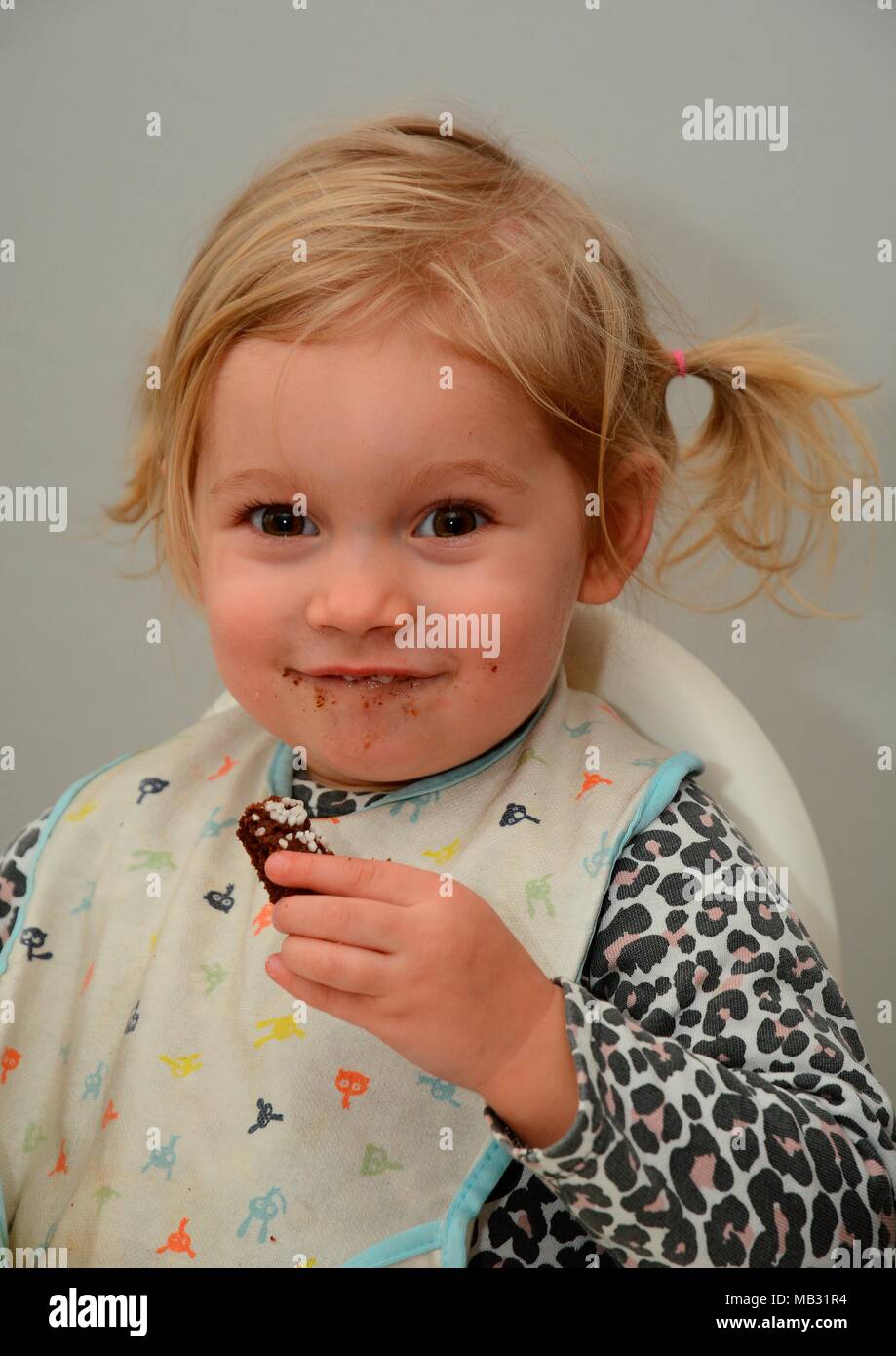 Little blond girl, two years old, smile while she eat a cake, Sweden Stock Photo