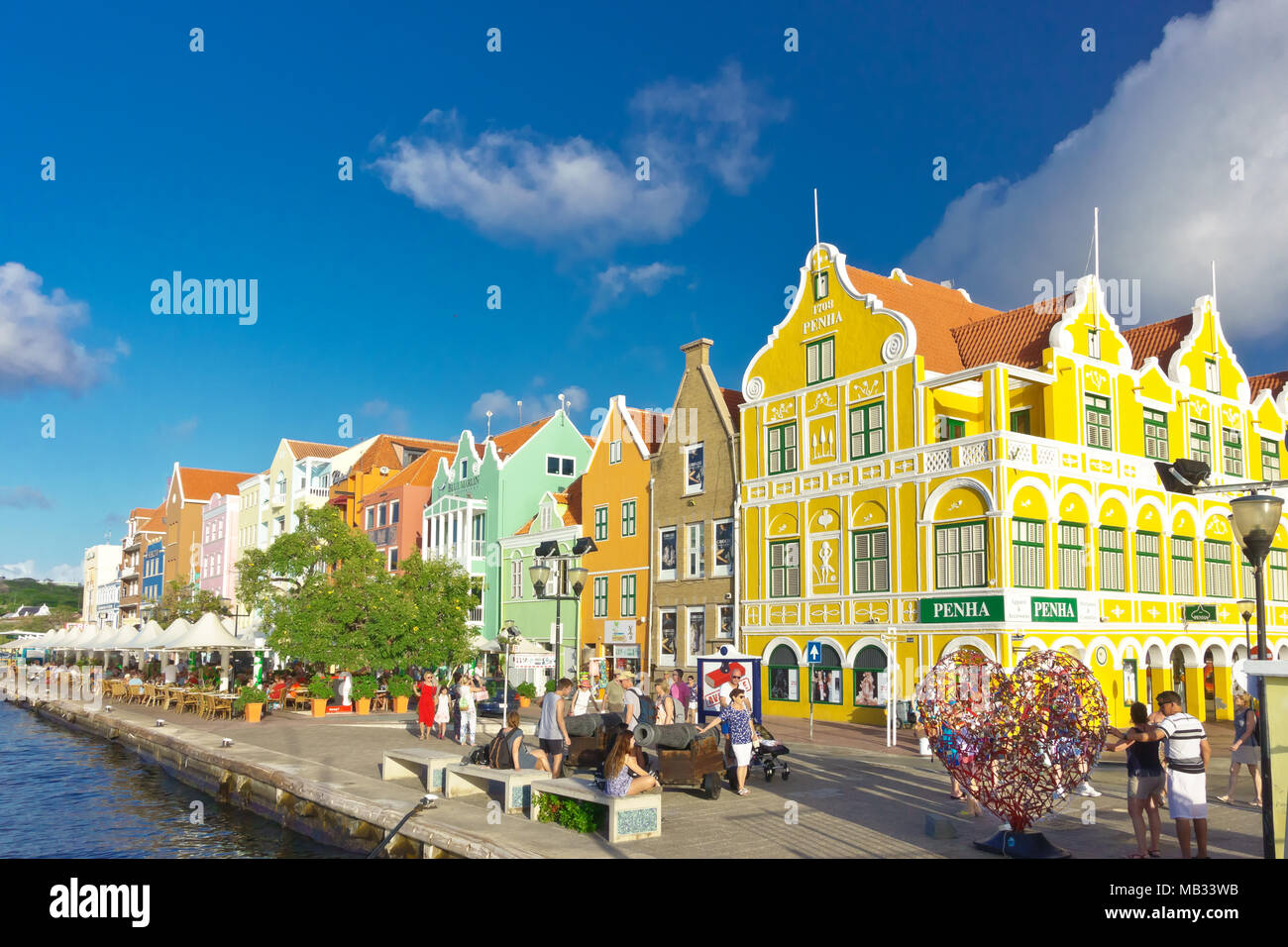 Iconic and colorful buildings at the Handelskade harbor waterfront with thr new 'Lock your Love' heart sculpture, Punda district of Willemstad, Curaca Stock Photo