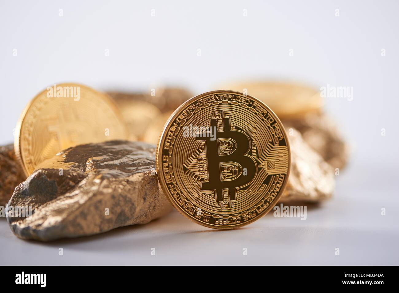 Shiny golden bitcoin being biggest cryptocurrency worldwide next to lumps  of gold isolated on white background. Blurred virtual electronic digital  money blockchain mining futuristic banking finance Stock Photo - Alamy