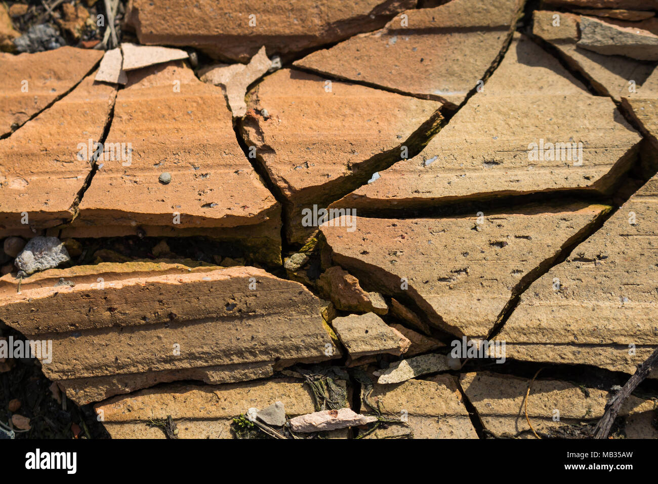 Detail of an orange broken brick in the sunlight at a junkyard. Stock Photo
