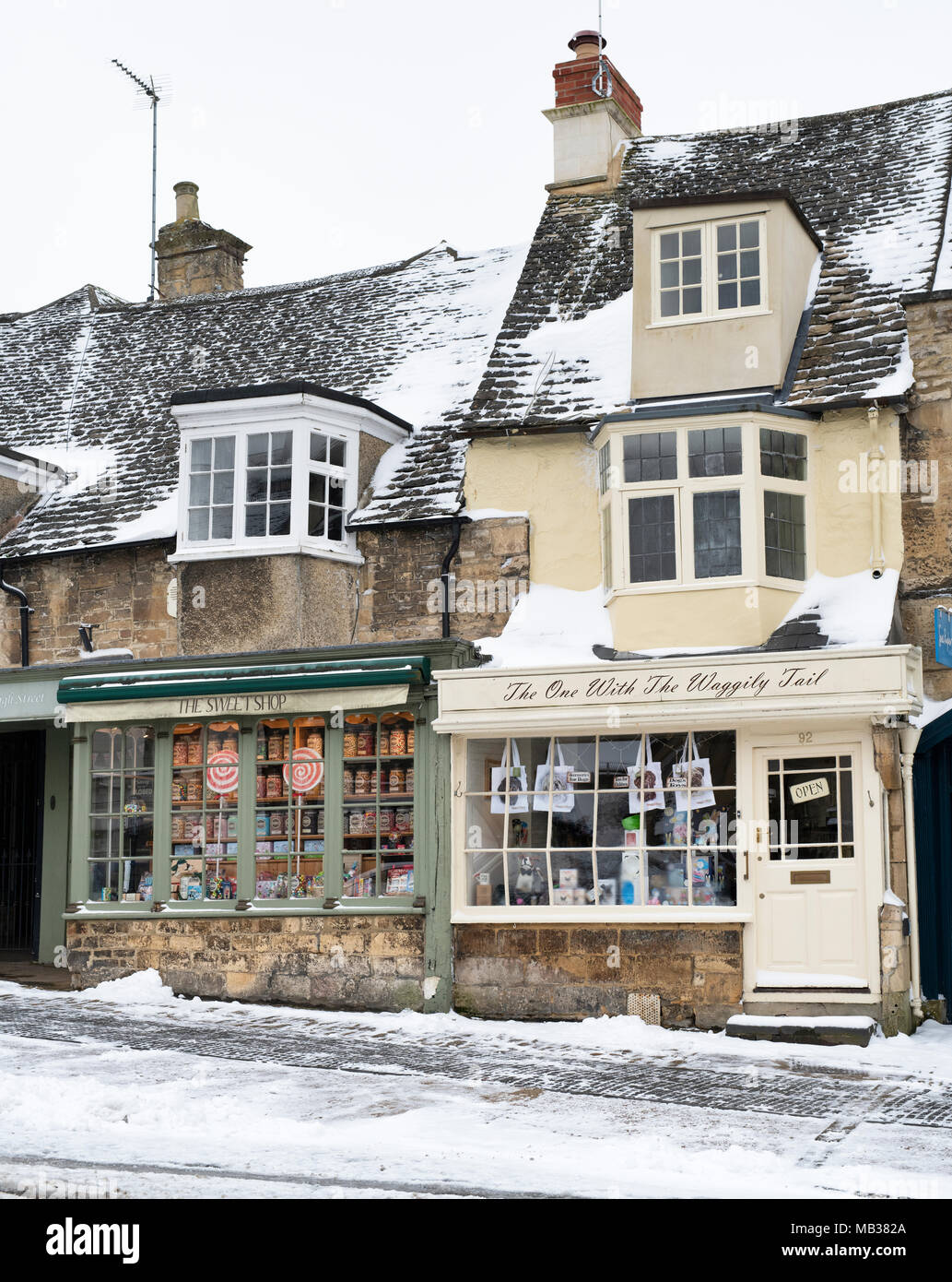 Sweet shop and pet shop on the high street in the snow. Burford, Cotswolds, Oxfordshire, England Stock Photo