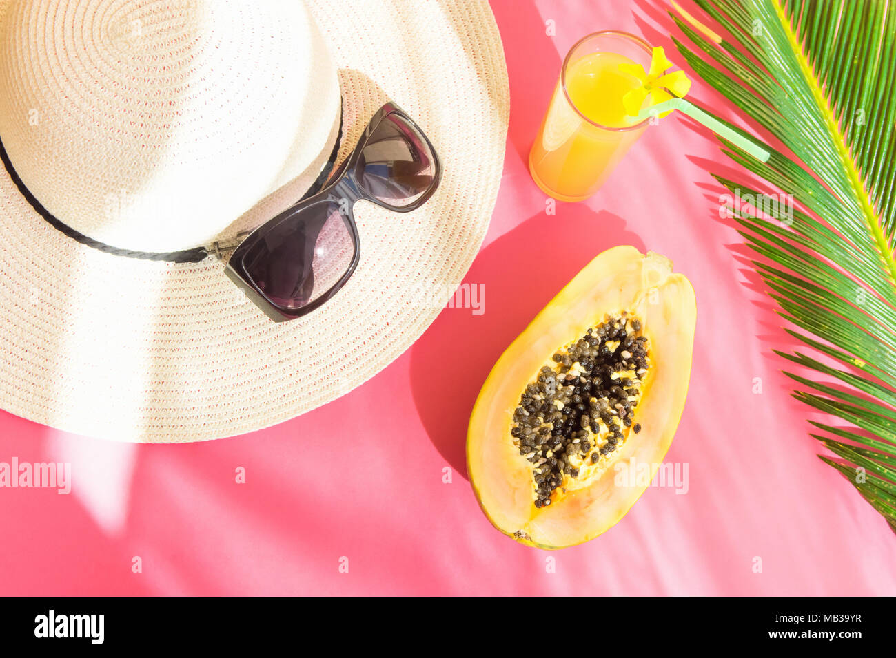 Straw Hat Sunglasses Tall Glass with Fresh Citrus Tropical Fruit Juice Papaya Palm Leaf on Pink Background. Sunlight Leaks. Summer Seaside Vacation Fa Stock Photo