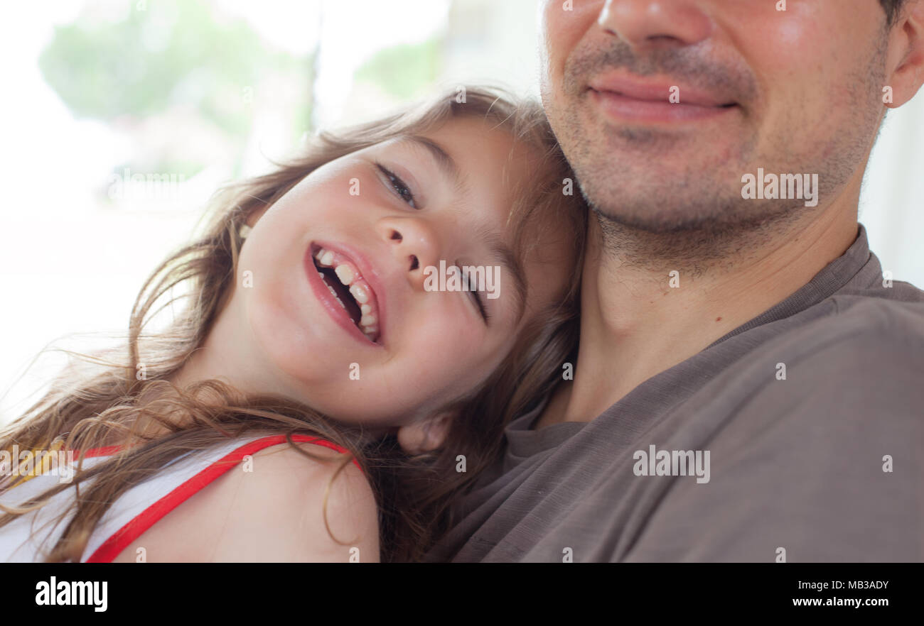 Close-up of a young smiling girl embraced by her father. Stock Photo