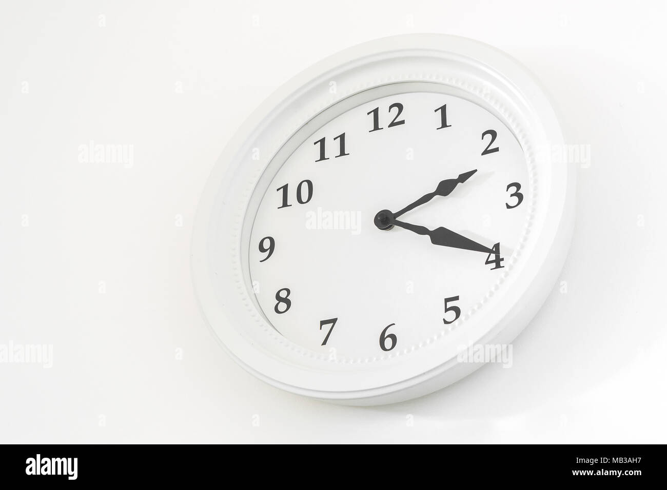A white clock hanging on a white wall Stock Photo Alamy